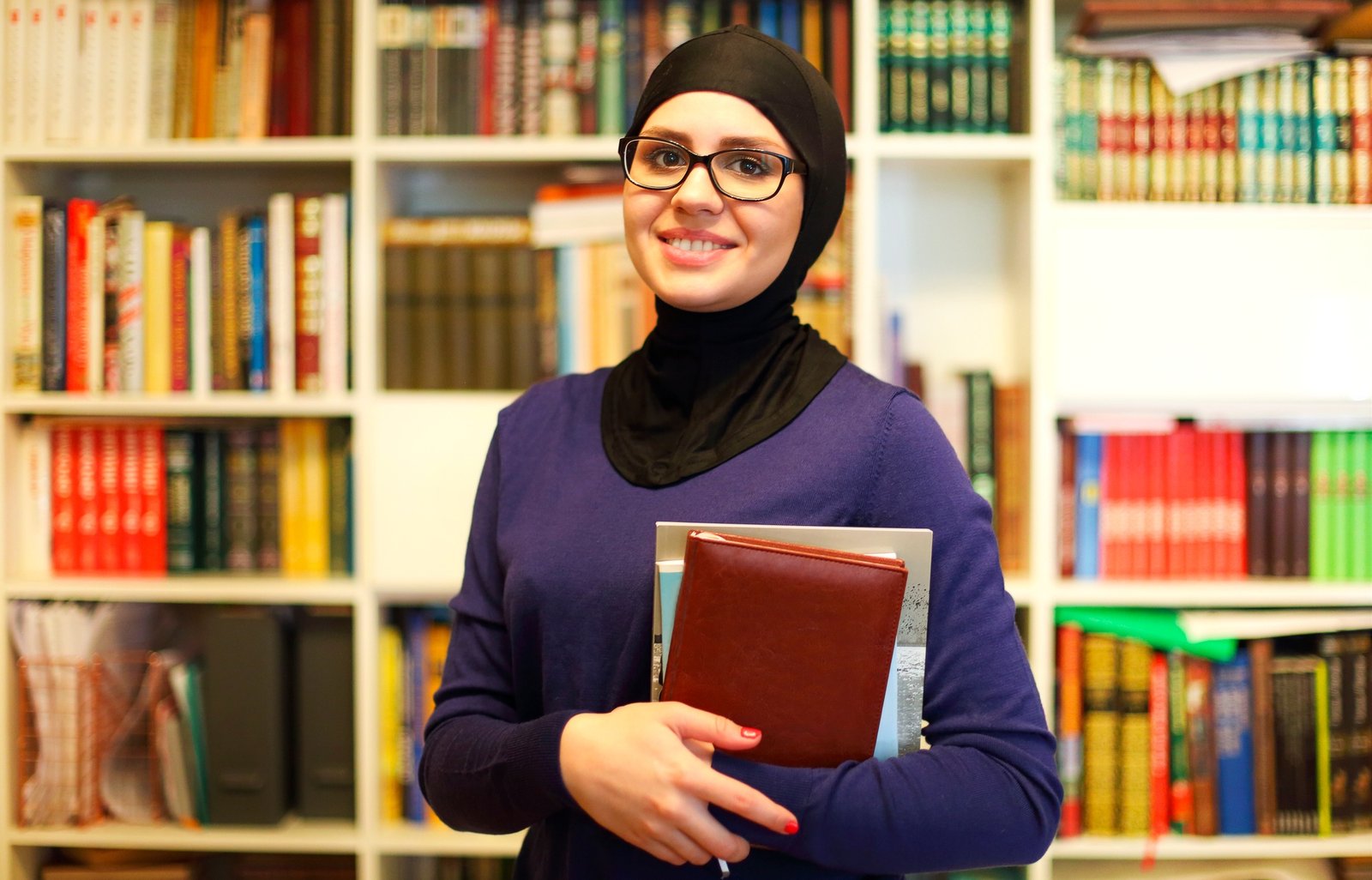 Smiling Islamic student with books in library
