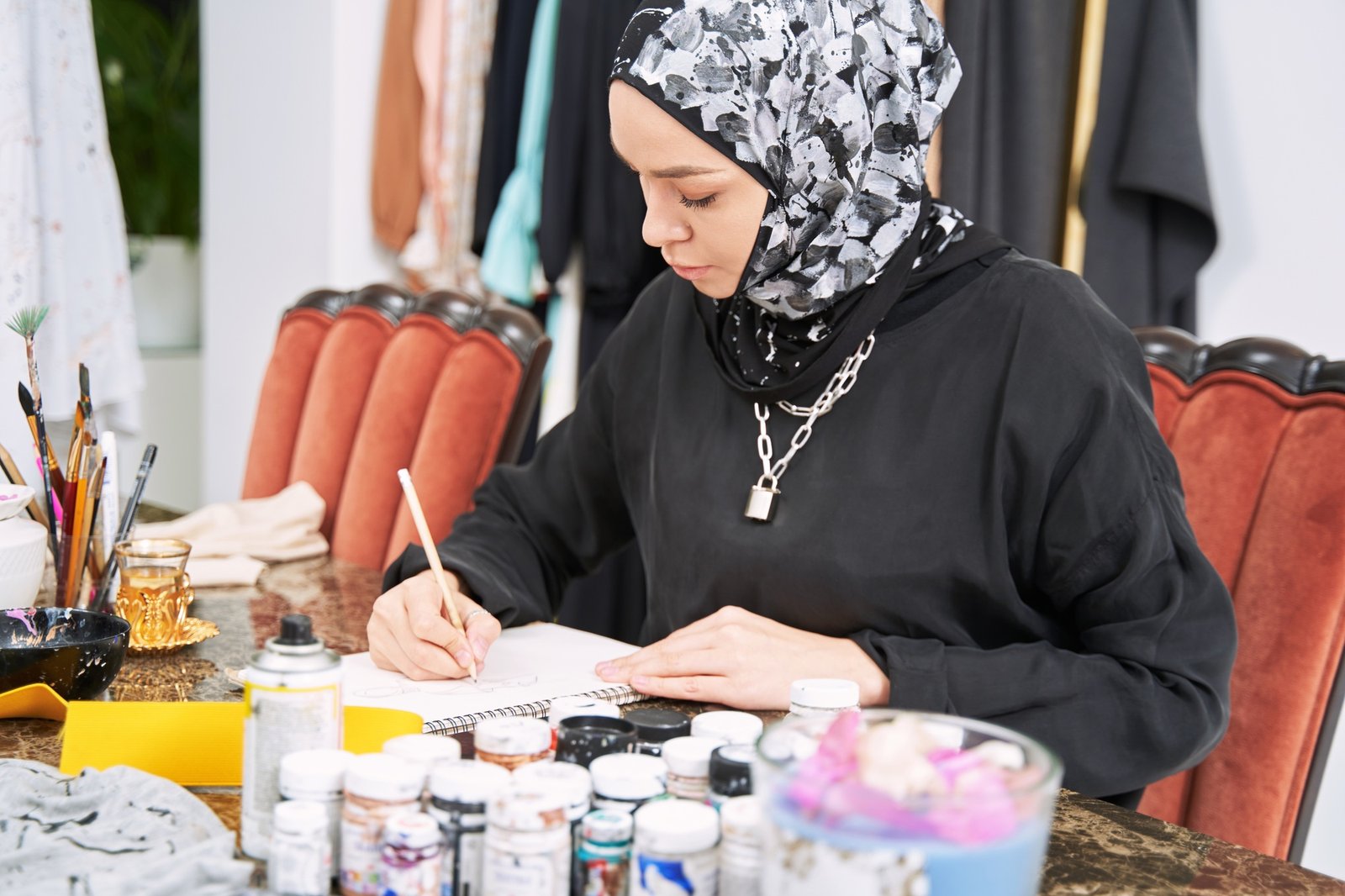 Stylish muslim female designing handmade clothes in studio